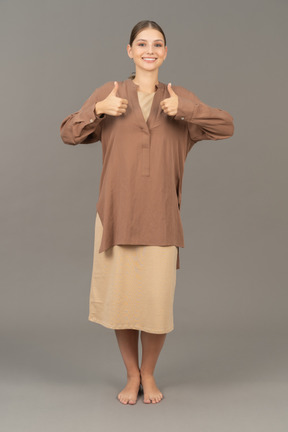 Front view of young barefoot woman smiling and showing thumbs up