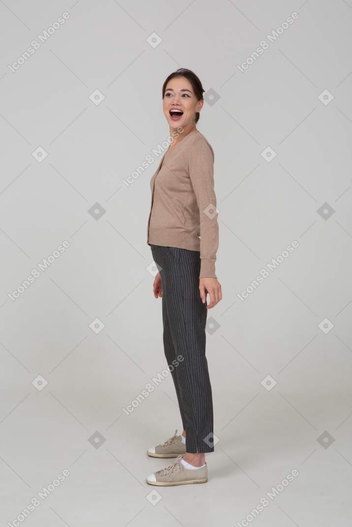 Vista laterale di una donna sorridente sorpresa in pullover beige
