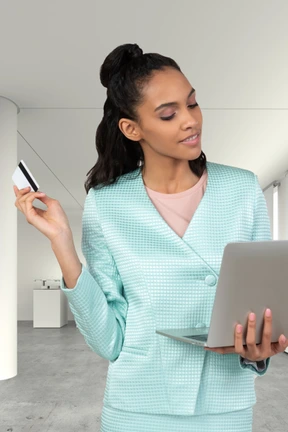 A woman holding a laptop and a credit card