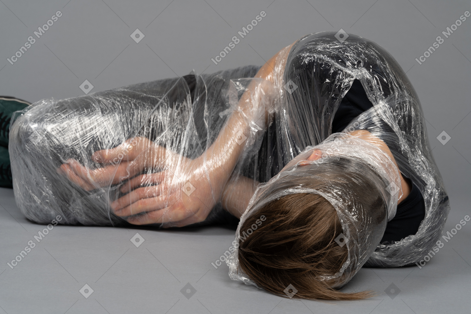 Jeune homme couché enveloppé dans du plastique