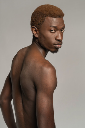 Portrait of topless young man looking over shoulder