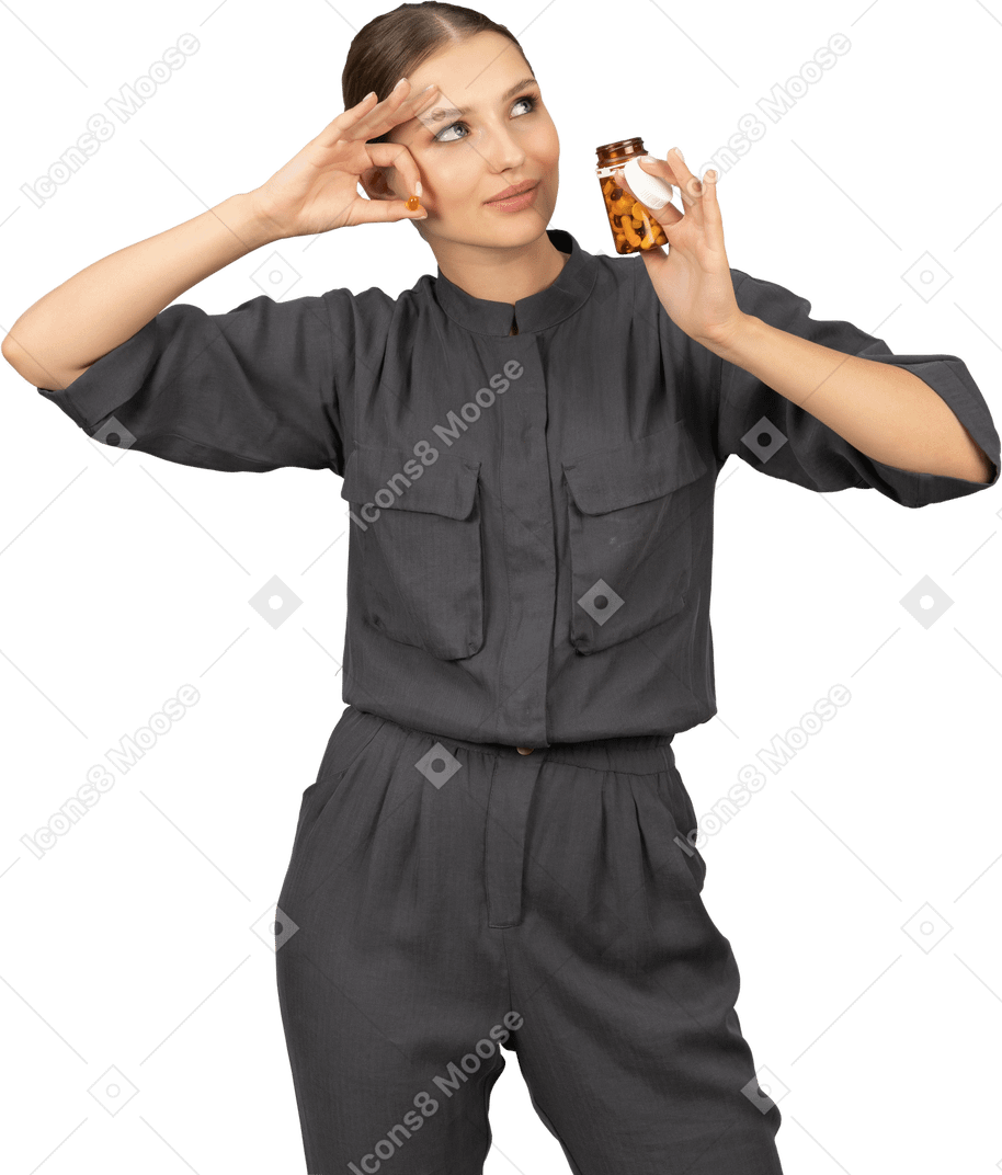 Front view of a young woman in a jumpsuit taking pills out of a jar