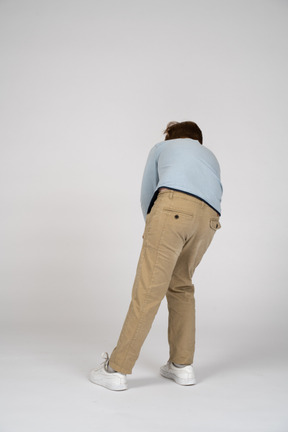 Back view of a boy bending down and touching knee