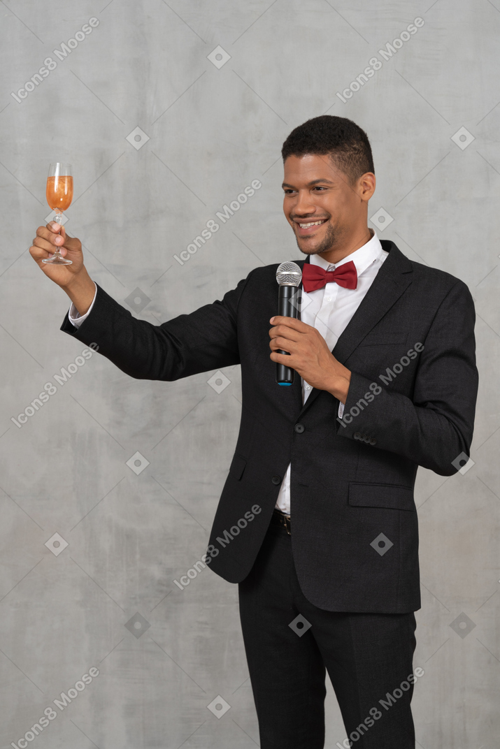 Lächelnder mann mit einem mikrofon, das sein glas erhebt