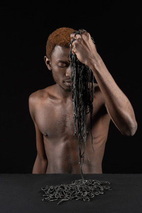 Vista frontal de un joven afro sosteniendo un brazado de pasta