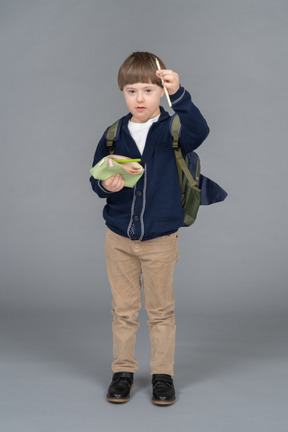 Retrato de um menino com uma mochila segurando um lápis