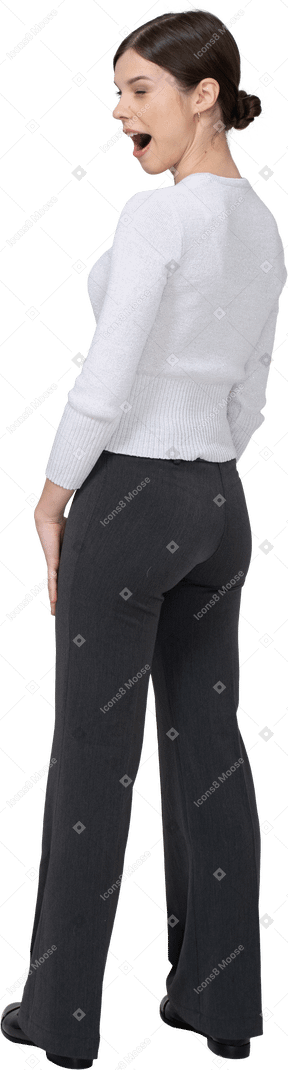 Vista posterior de tres cuartos de una mujer joven bostezo en ropa de oficina