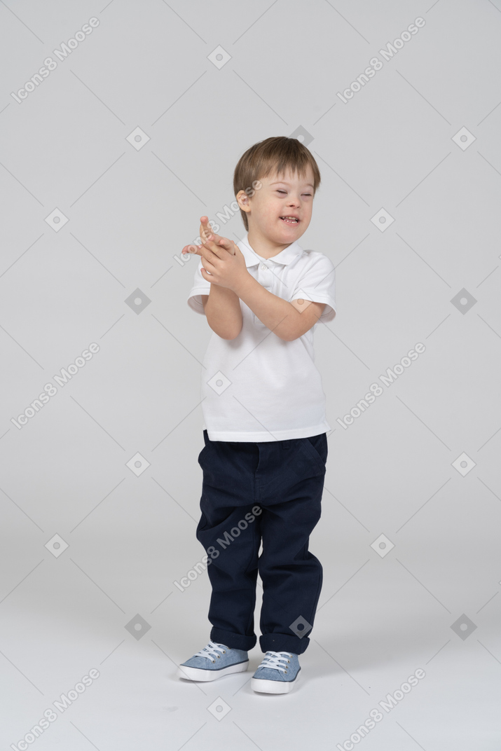 Smiling little boy holding his hand with closed eyes