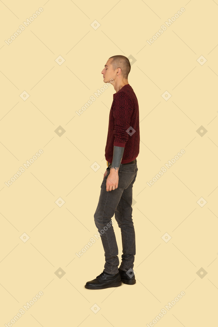 Вид сбоку на молодого человека в красном свитере, стоящего на месте