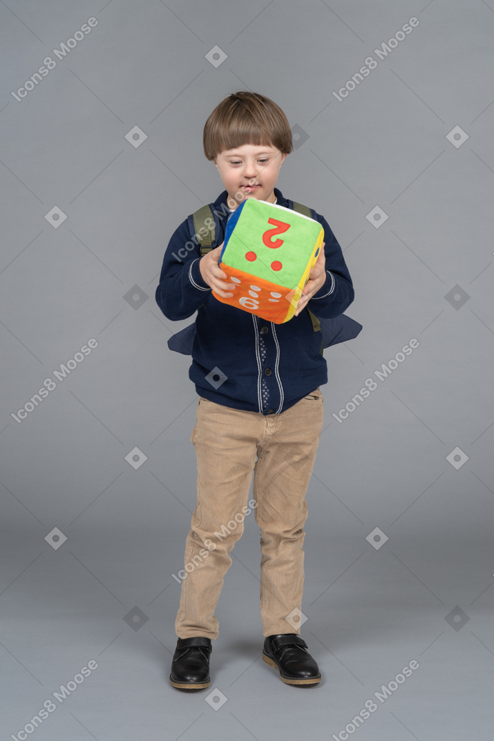 Little boy with a backpack holding plush dice
