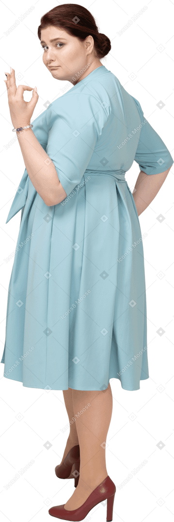 Side view of a woman in blue dress showing ok sign