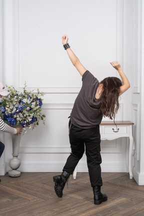 Back view of a young female dancing while raising her hands