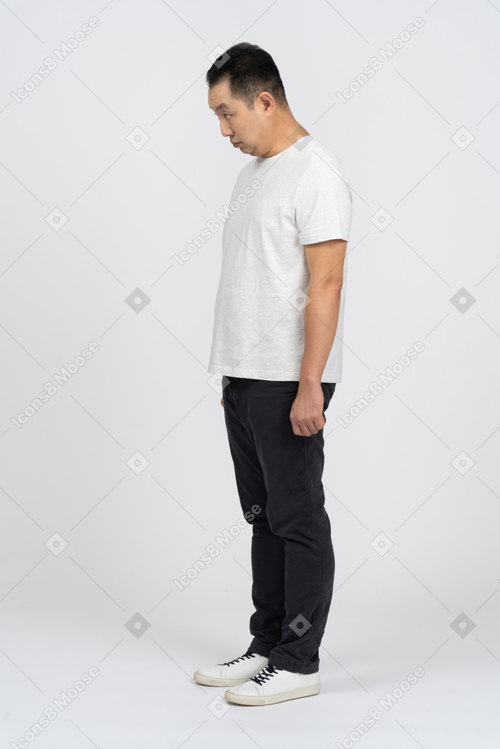 Man in casual clothes standing still and bending head down