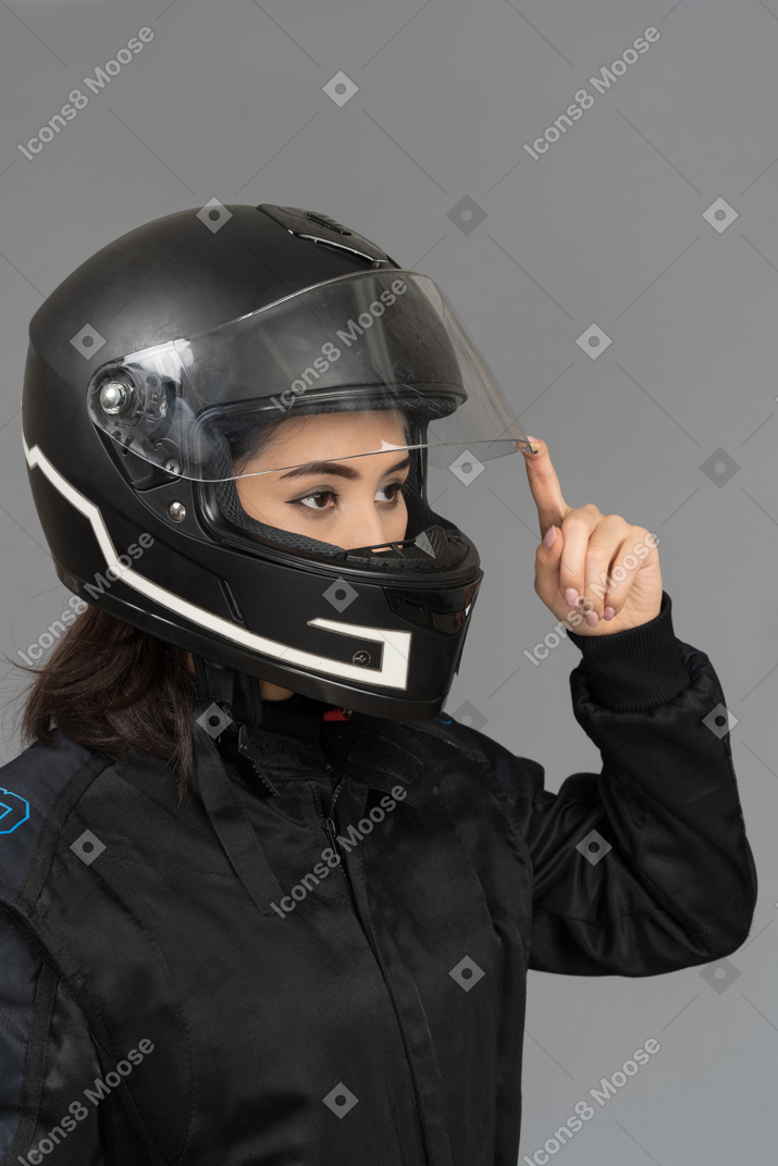 Um motociclista feminino abrindo uma viseira de capacete