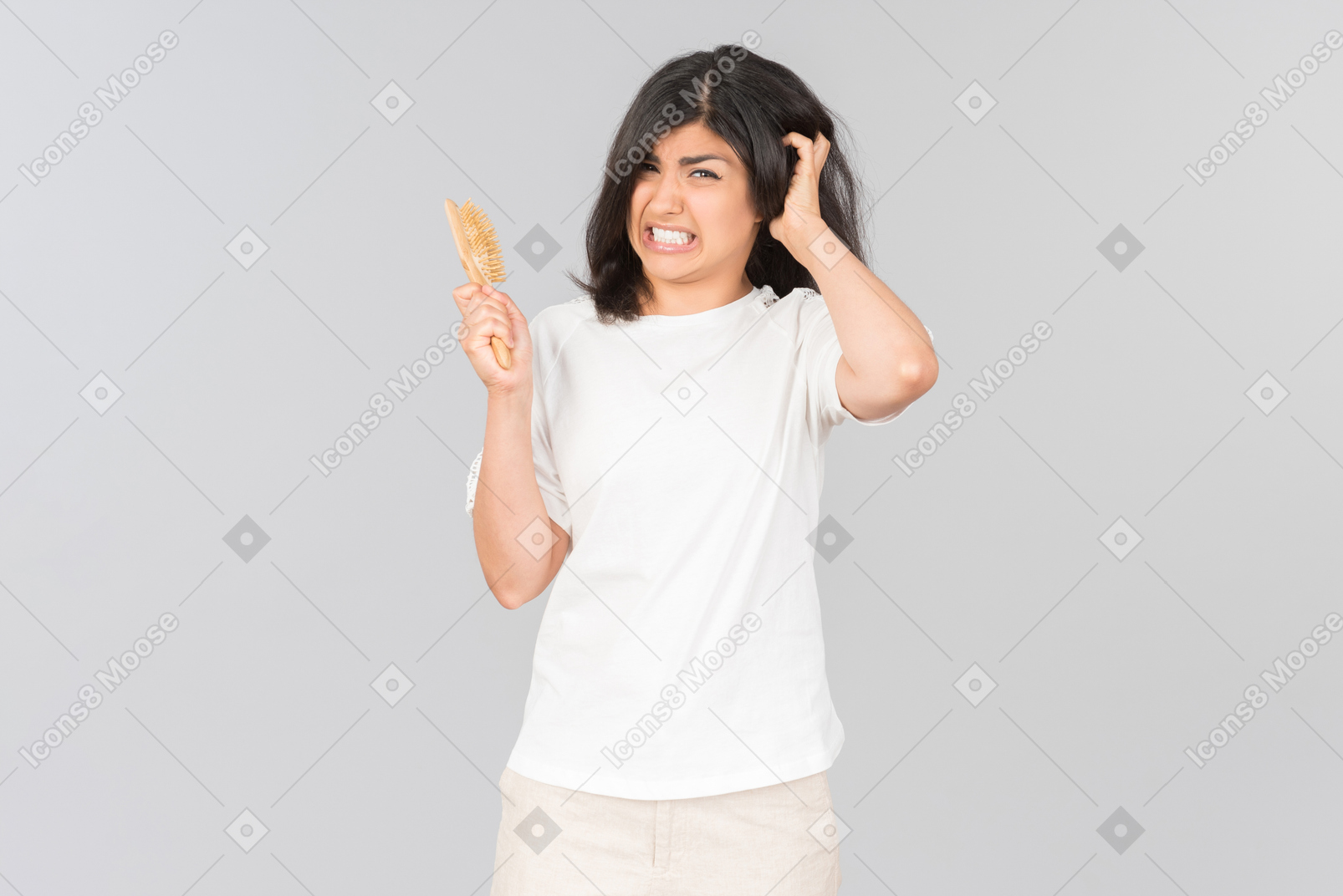 Irritated young indian woman holding hairbrush