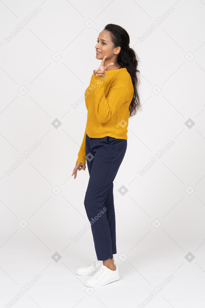 Side view of a happy girl in casual clothes showing v sign