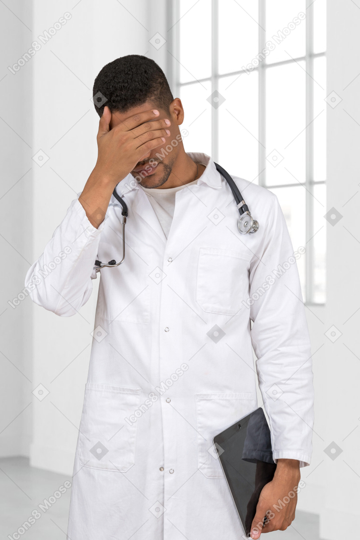 Médico homem cansado, tocando sua cabeça