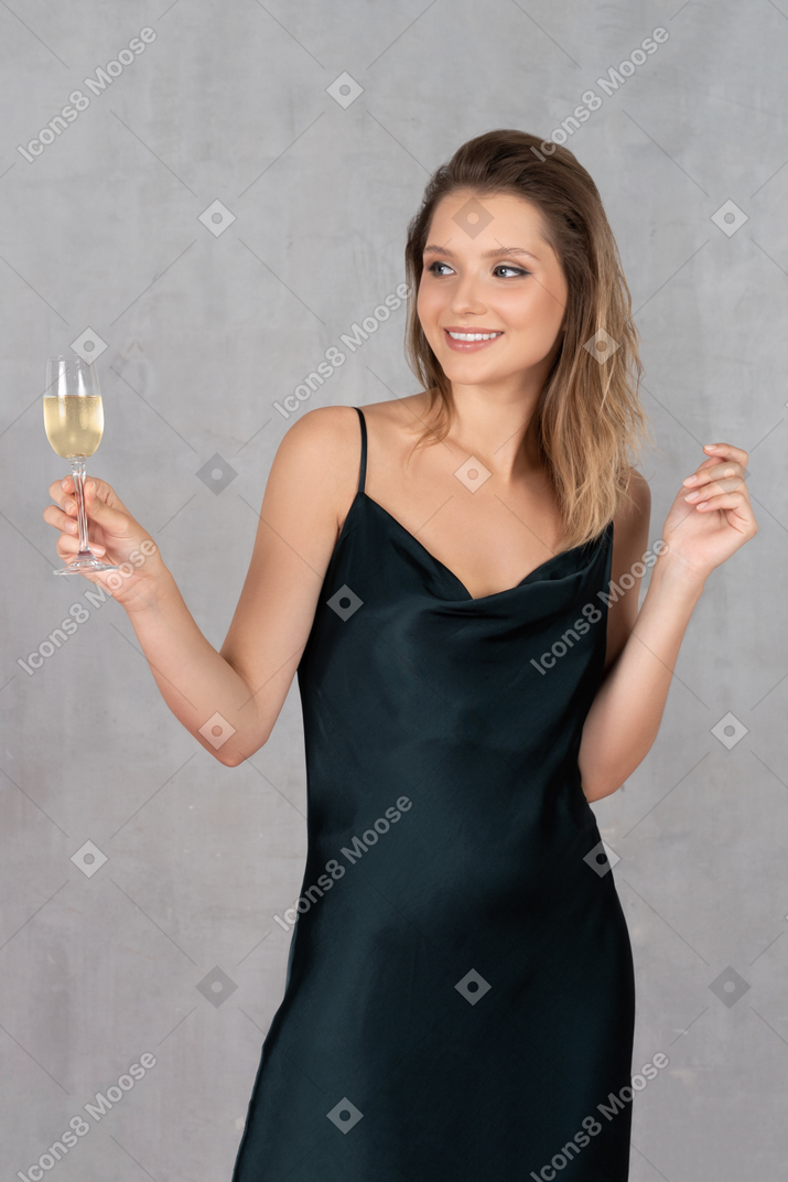 Front view of a young woman in night gown holding a glass of champagne