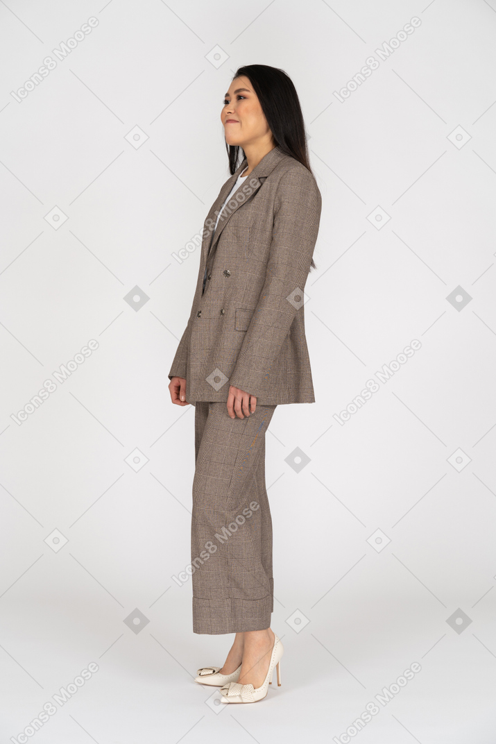Вид в три четверти ухмыляющейся молодой леди в коричневом деловом костюме