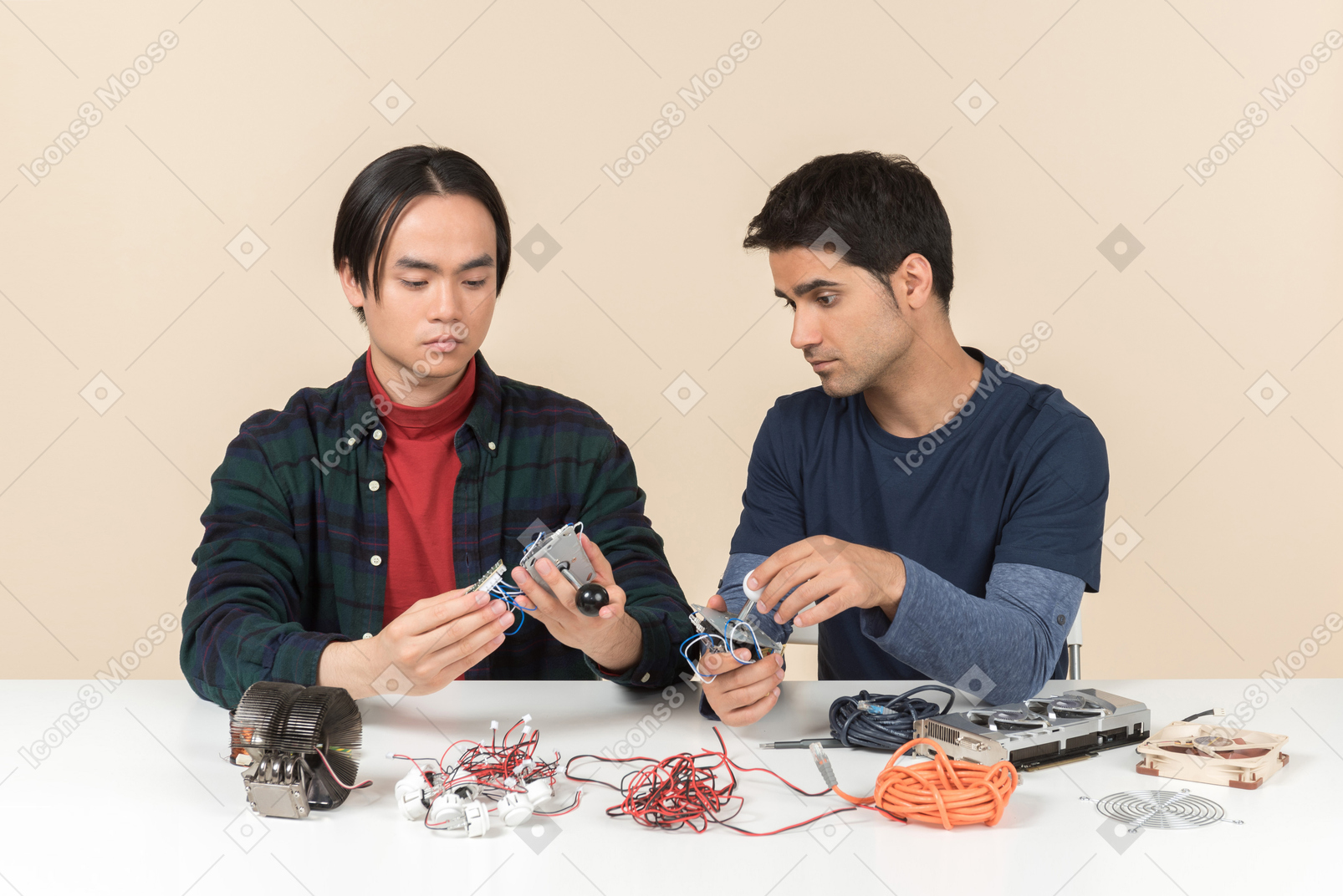 Two young geeks sitting at the table and fixing some details