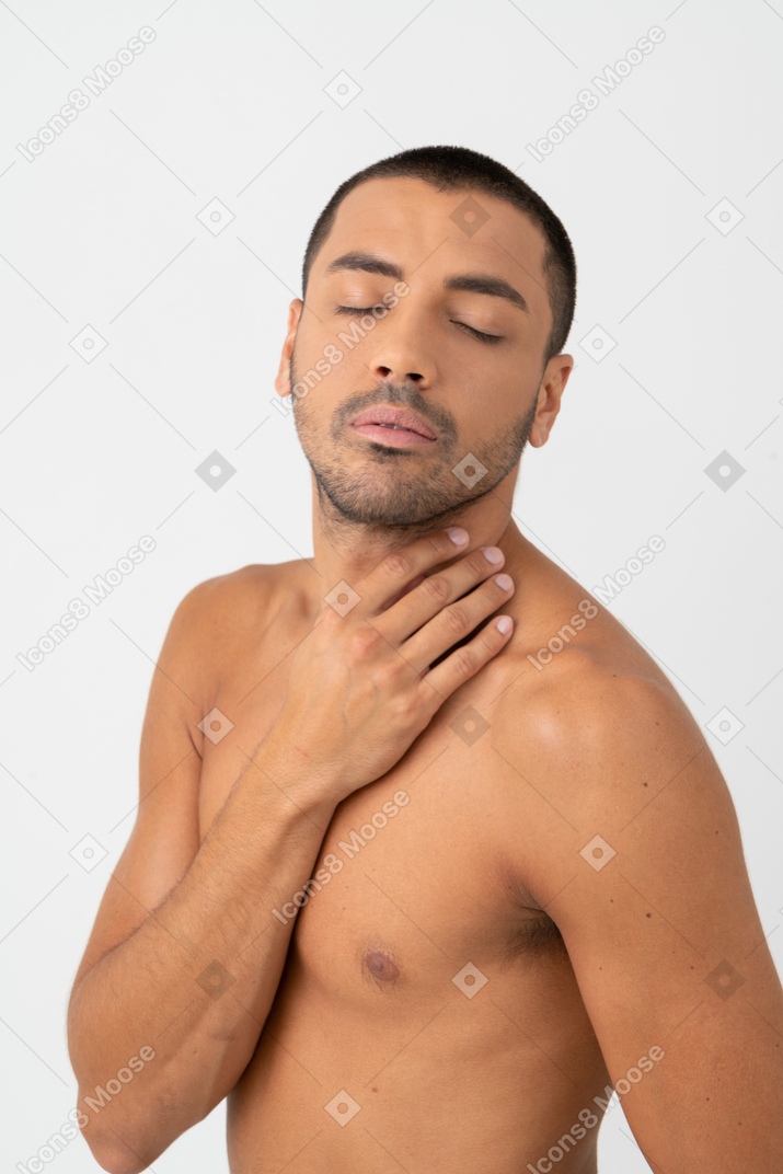 Barechested young man touching neck with his eyes closed