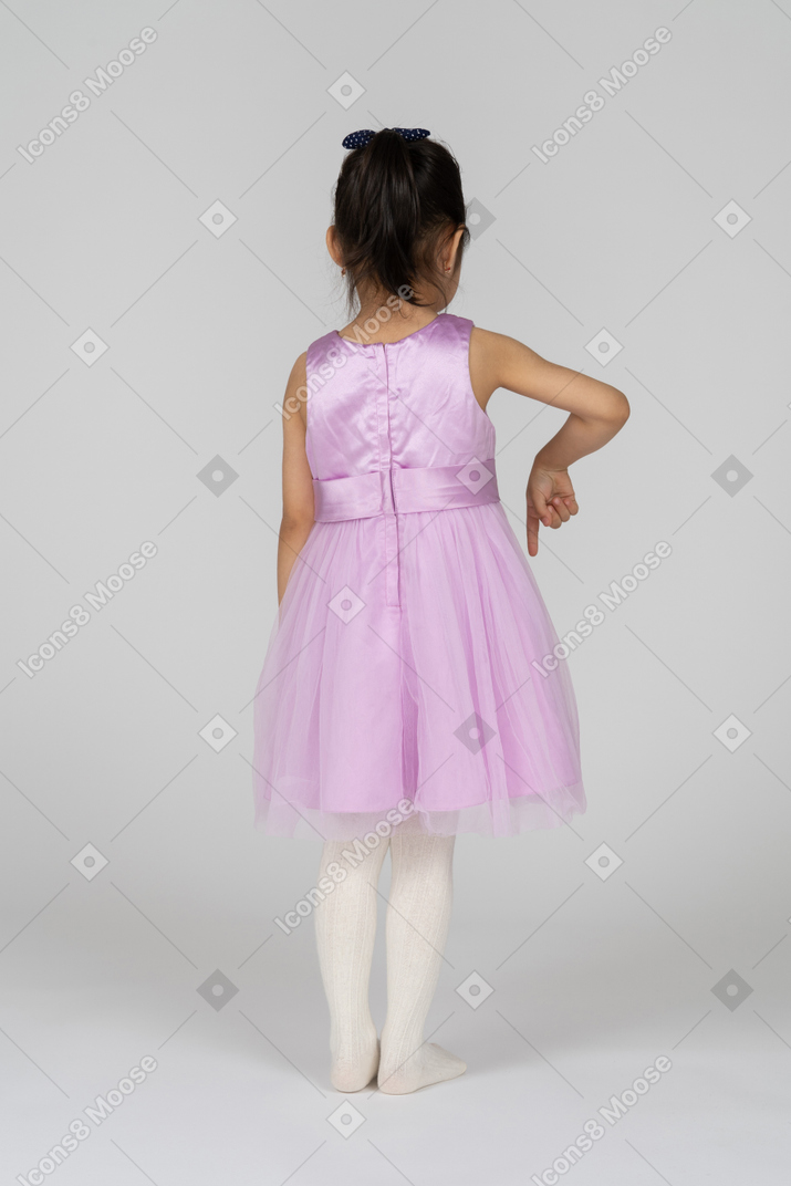 Vista traseira de uma menina em um vestido de tutu apontando para baixo