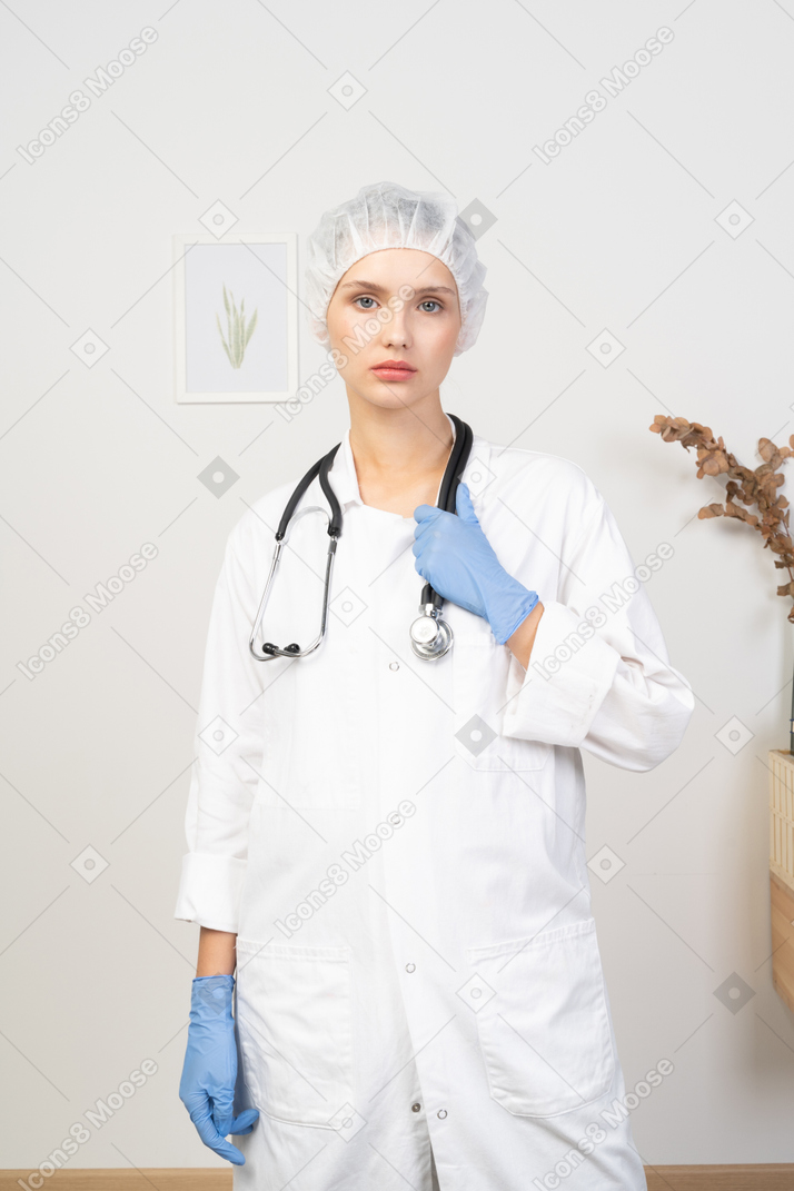 Vista frontale di una giovane dottoressa che tiene in mano uno stetoscopio