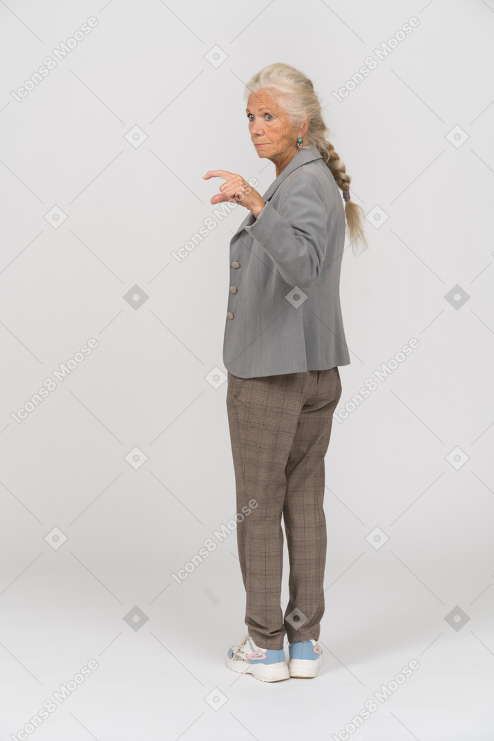 Vista trasera de una anciana en traje mostrando el tamaño de algo