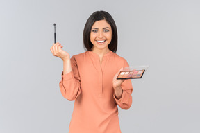 Indian woman holding eyeshadow and eye brush