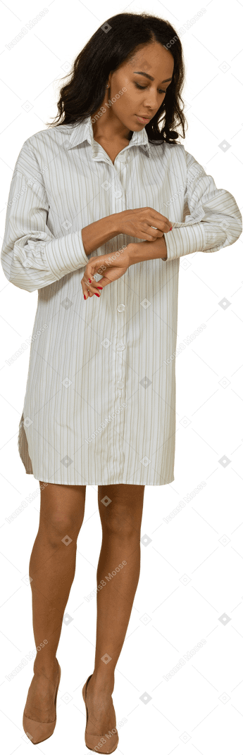 一个穿着白色连衣裙的深色皮肤的年轻女性，扣紧她的袖子的前视图