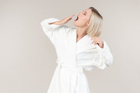Young woman in bathrobe yawning