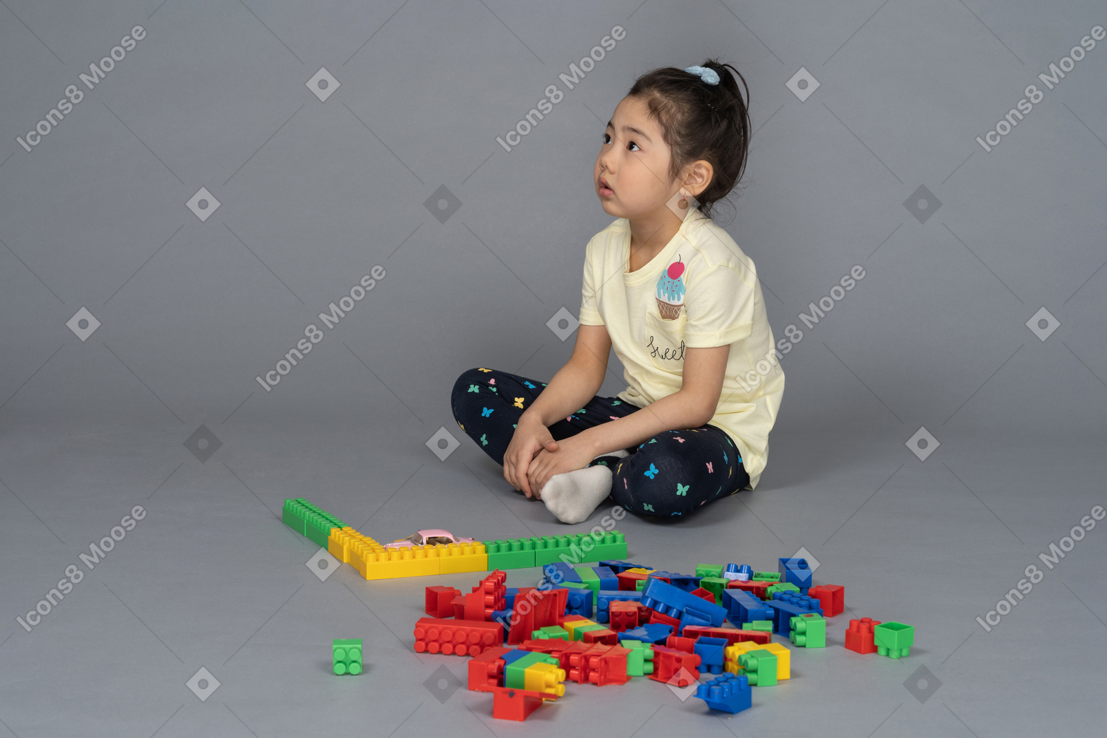 Side view of a little girl sitting beside a building set