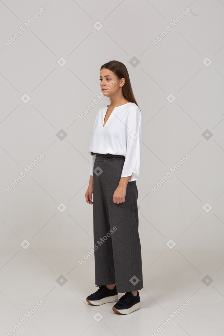 Vista di tre quarti di una giovane donna in abiti da ufficio che guarda da parte