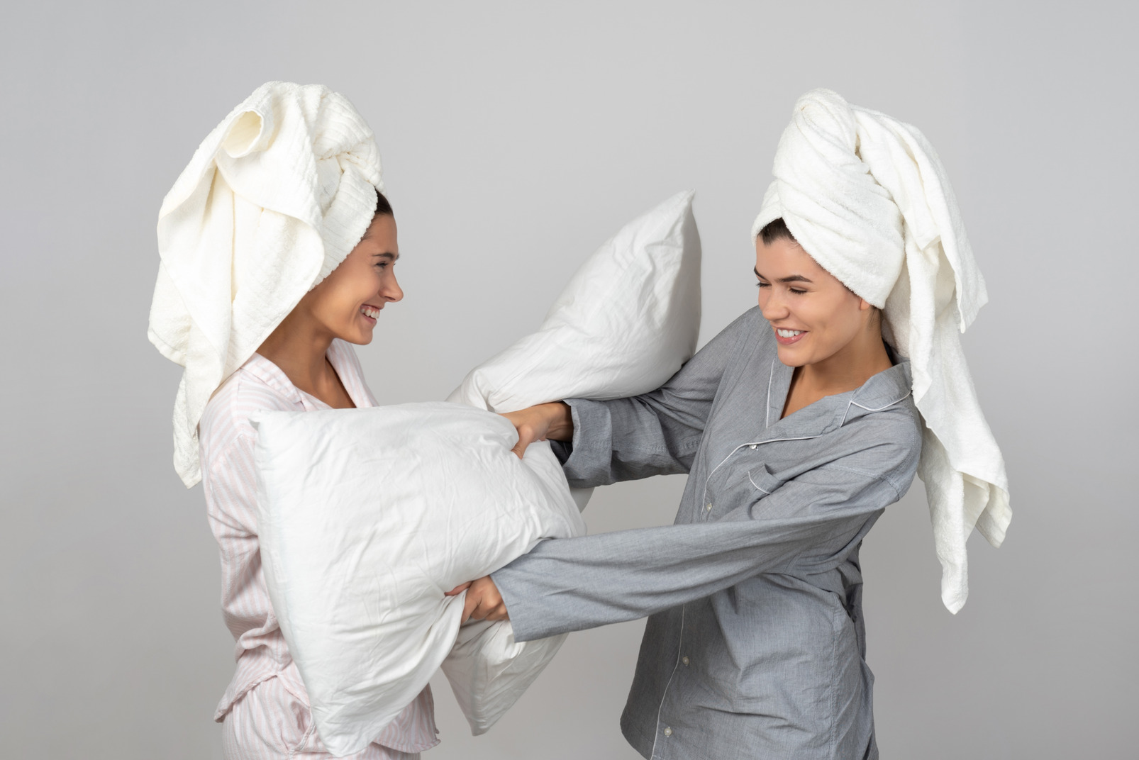 Two young women pillow fighting