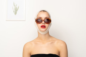 Mujer joven con vendaje en la cabeza con gafas de sol