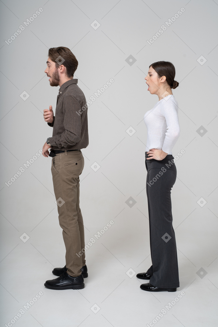 Vista lateral de um jovem casal bocejando com roupas de escritório