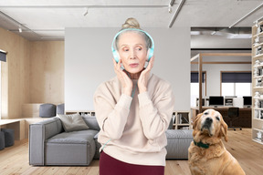 A woman with headphones on standing next to a dog