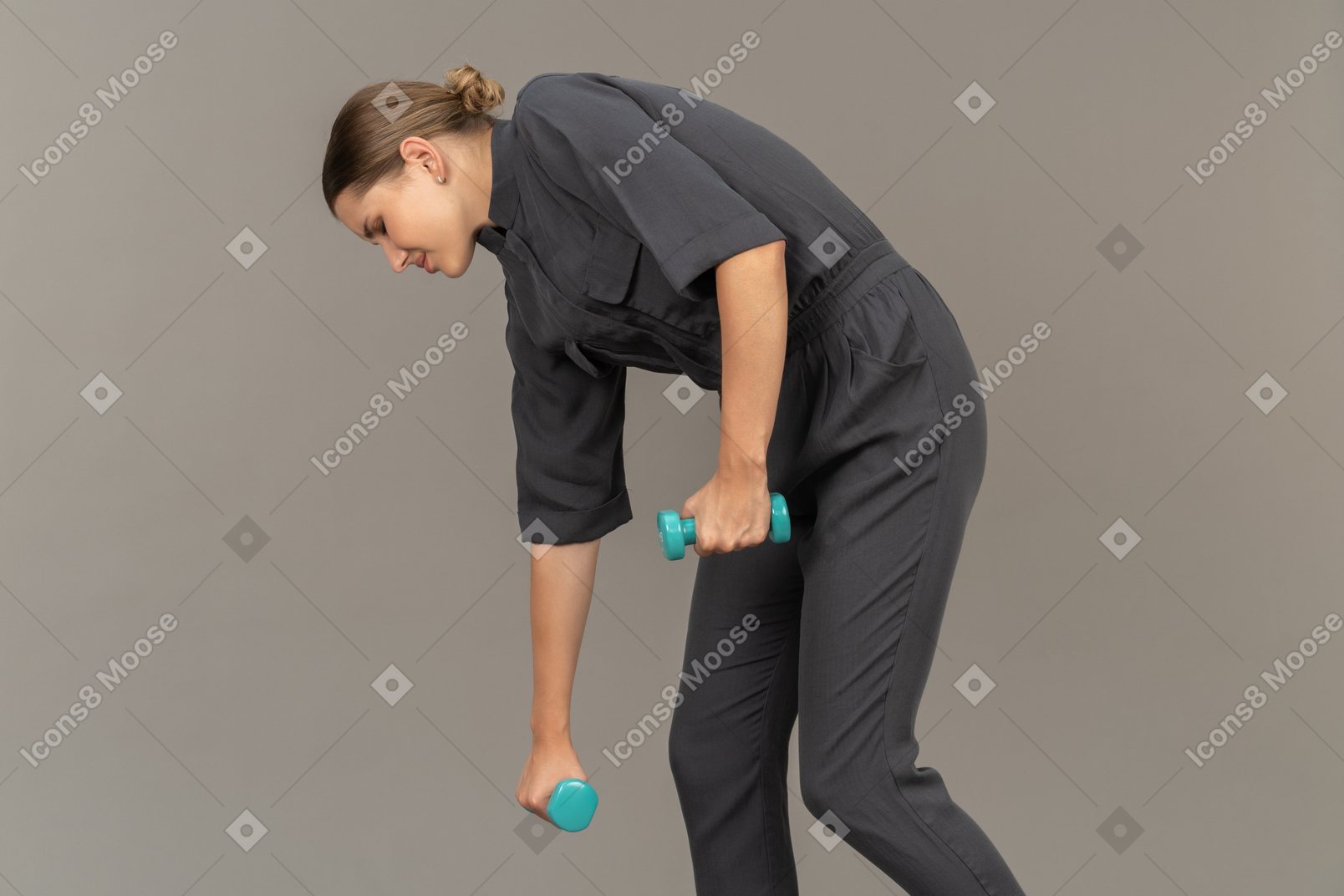 Vista laterale di una giovane donna in tuta che fa esercizi con manubri
