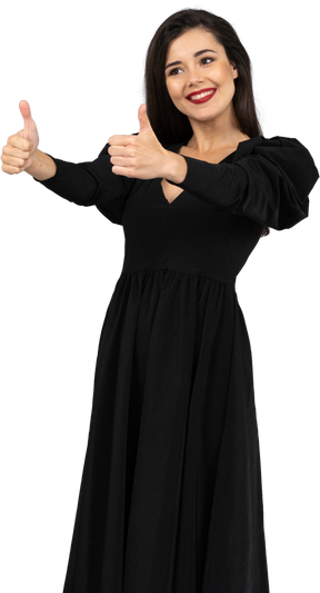Three-quarter view of a young lady in a black dress showing  thumbs up