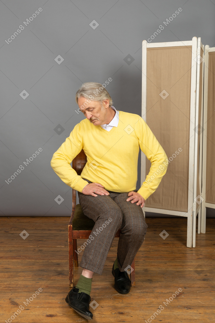 Man sitting on chair and looking down at his shoe