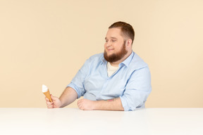 Big man sitting at the table and holding ice cream