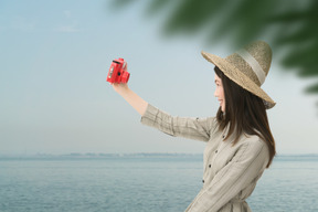 Young asian woman taking selfie with red vintage photo camera