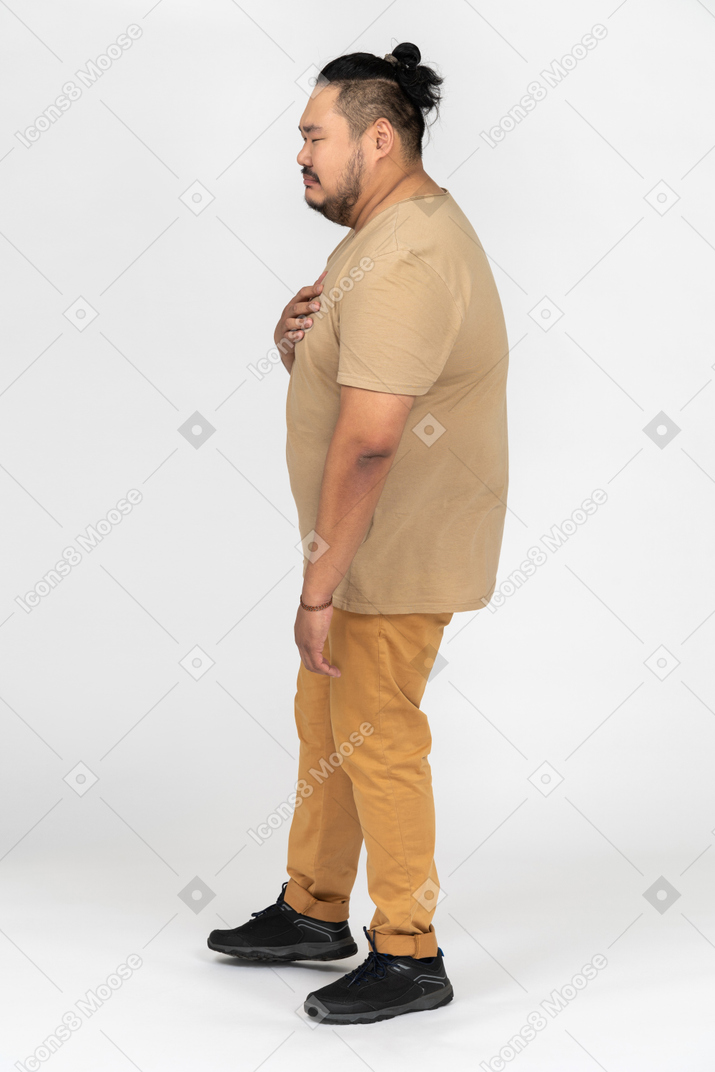 Sad lonely asian man standing in profile with closed eyes