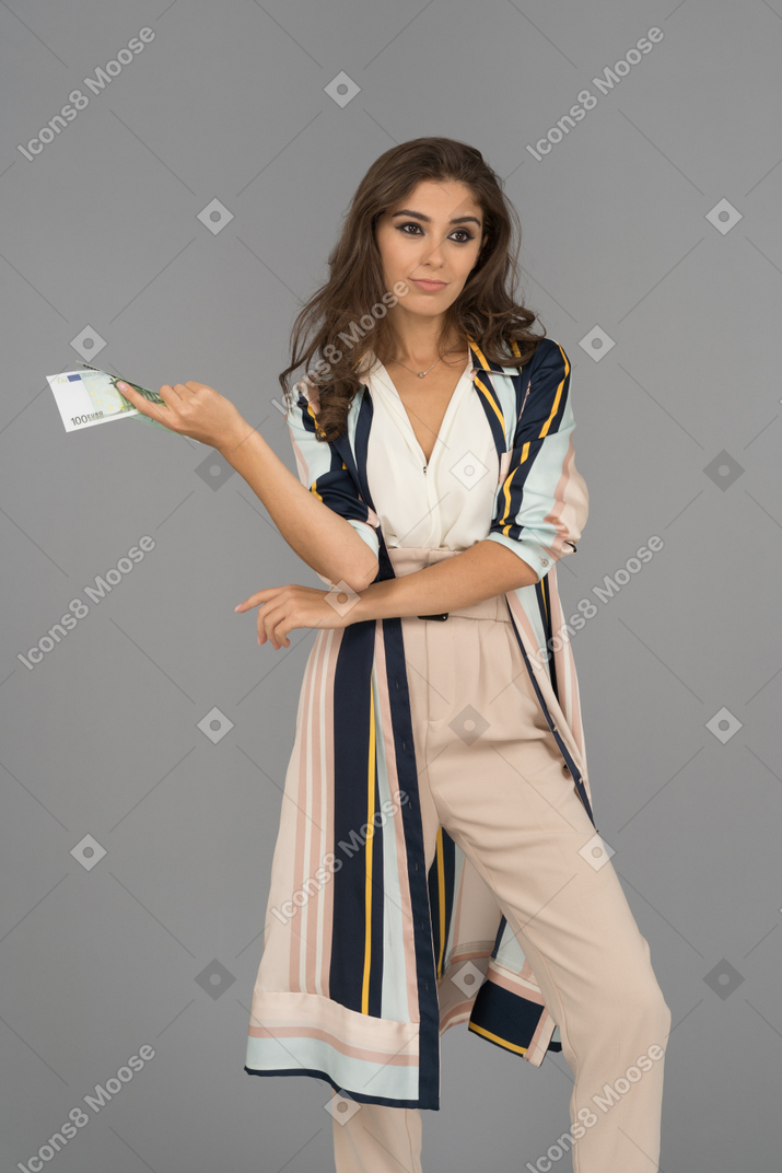 Unsatisfied young arab woman standing with a banknote in hand