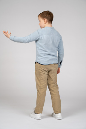 一个男孩伸出手臂站立的后视图