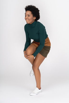 Cheerful african girl standing on one leg