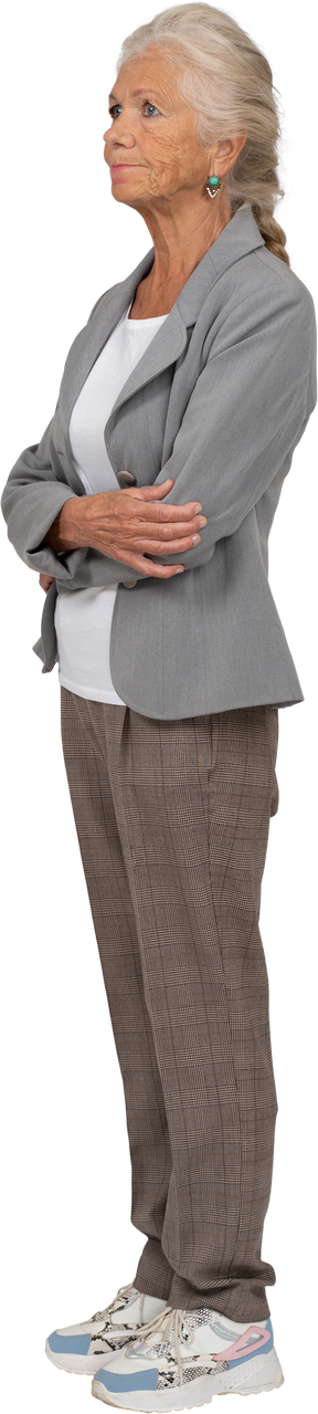 Seitenansicht einer alten dame im anzug, die mit verschränkten armen posiert