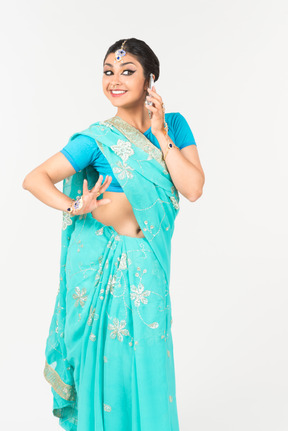 Young indian dancer in blue sari talking on the phone