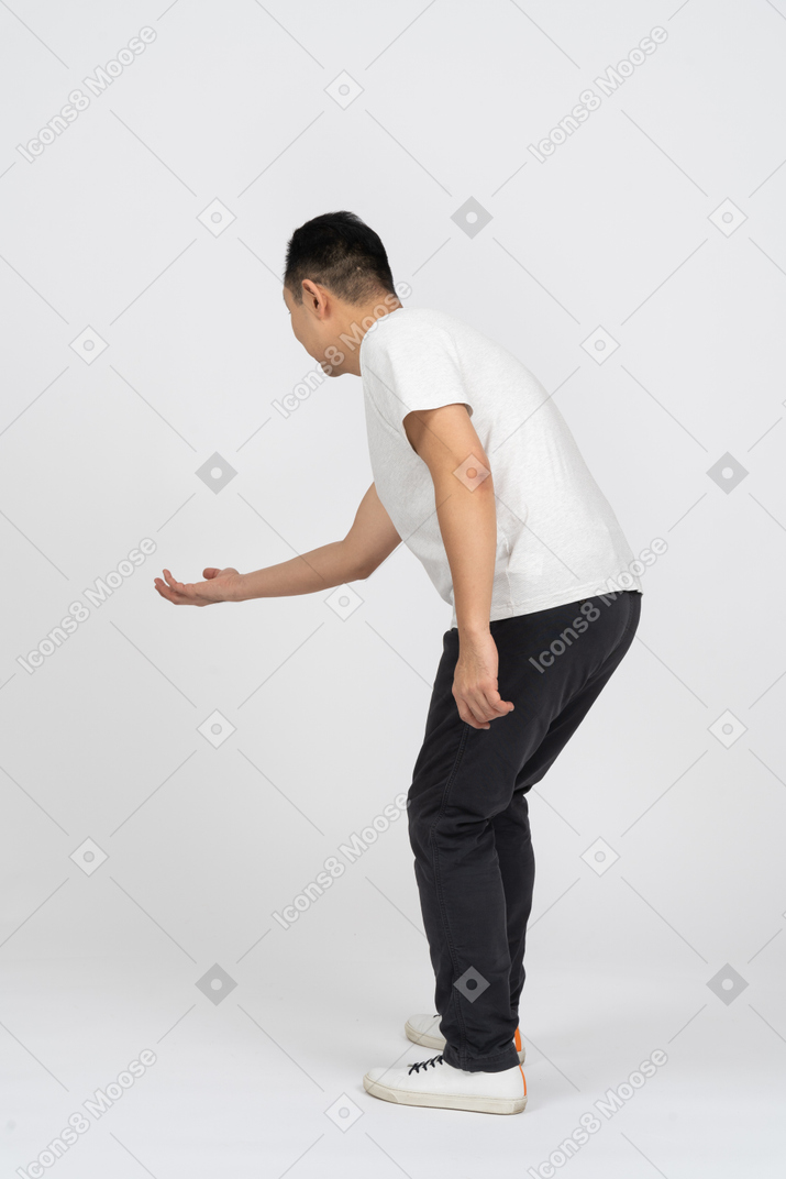 一个穿着休闲服的男人伸出手臂弯下腰的侧视图