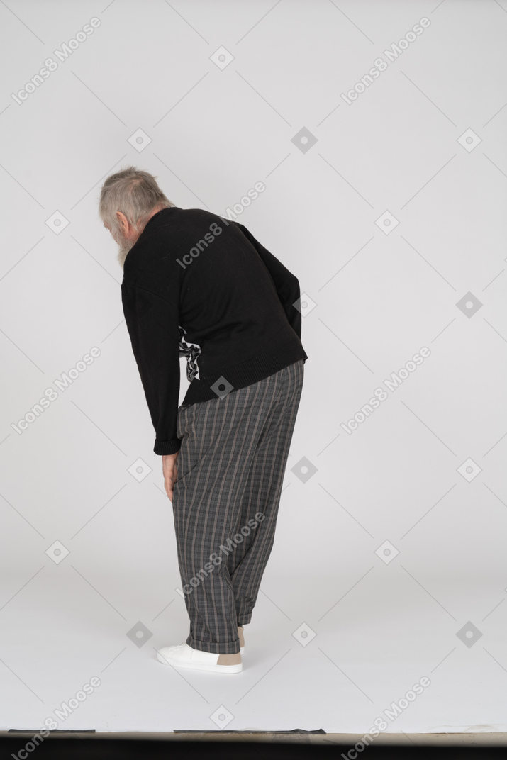 Rear view of old man groaning with pain in leg
